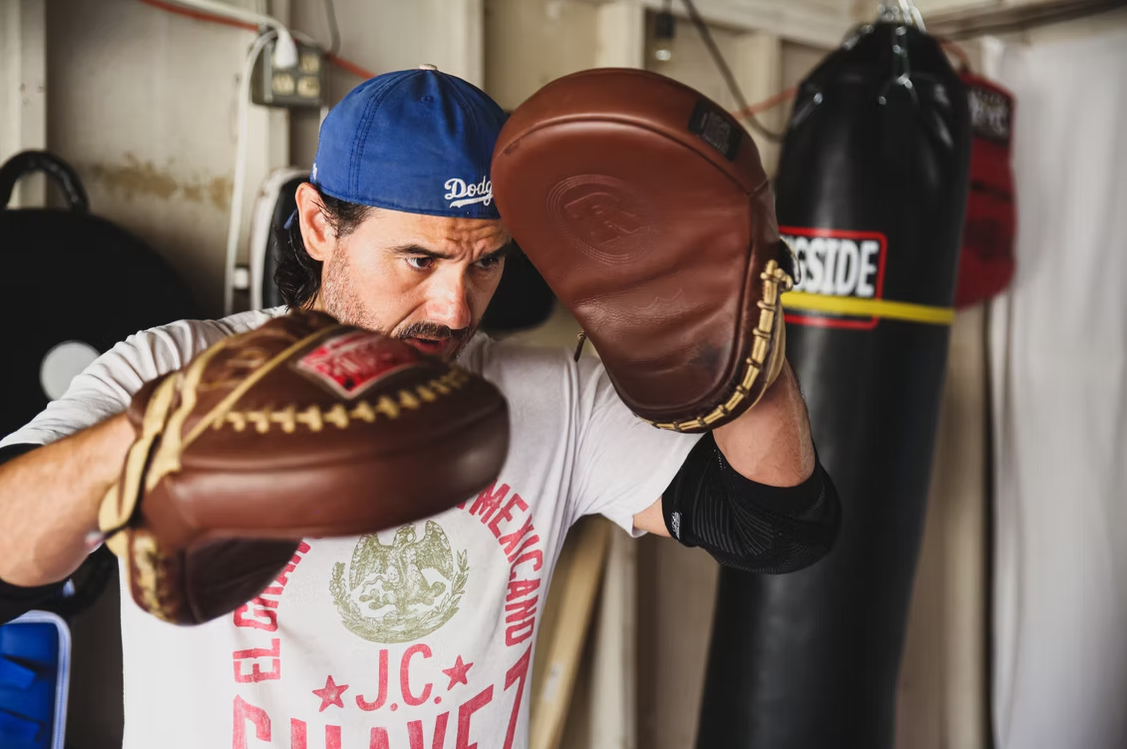 Coach Joe holding leather mitts for boxing fundamentals at Strikers Inc.